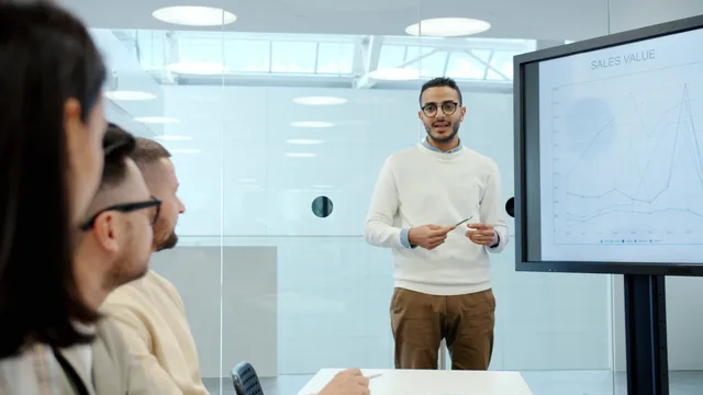 Professional presenting sales data on screen during office meeting. Deciding when an outbound offer needs to change