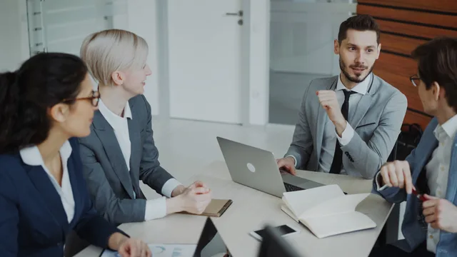 Business professionals engaged in a meeting around a conference table in a modern office space. Ideal customer profiles for outbound prospecting