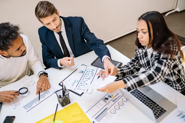 Business professionals engaging in a collaborative meeting with charts and documents. Outbound programme improvement