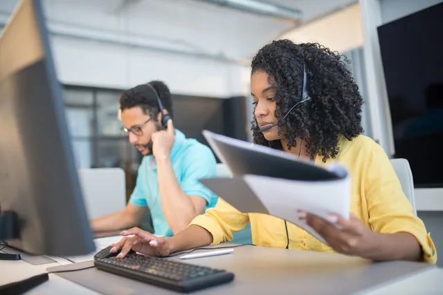 Two customer service representatives working with headsets in a modern office setting. Passing the prospect's own words rather than inflated claims