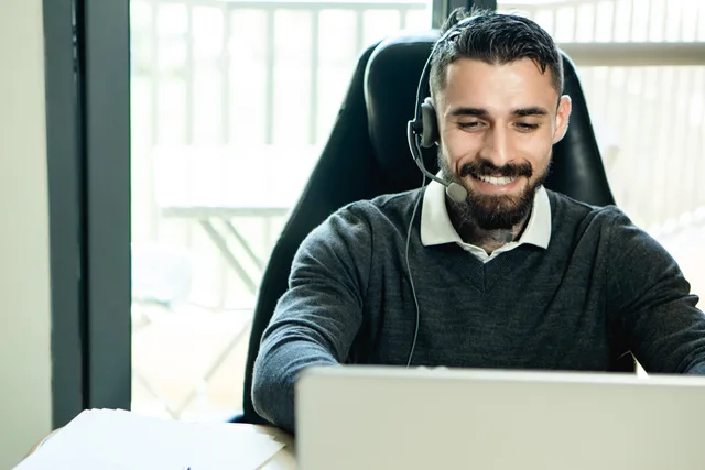 A friendly customer support agent wearing headphones, working in an office environment. Reviewing accounts that repeatedly receive no useful response